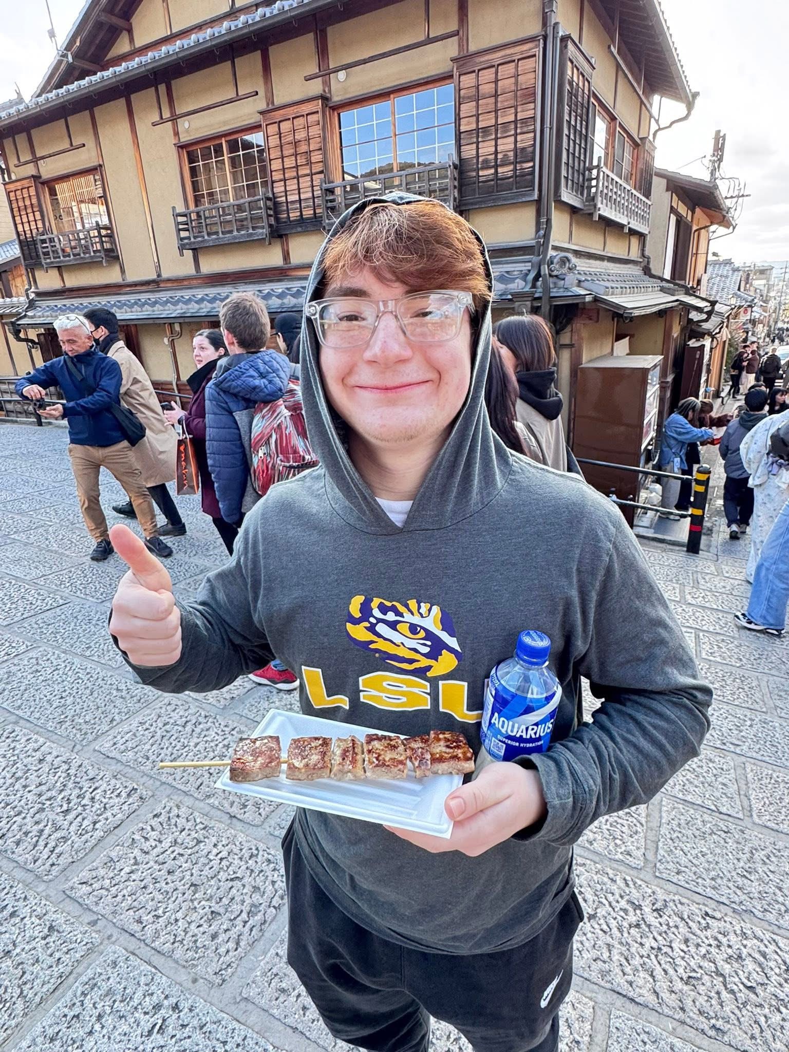 Holden in LSU hoodie with street food on Ninenzaka